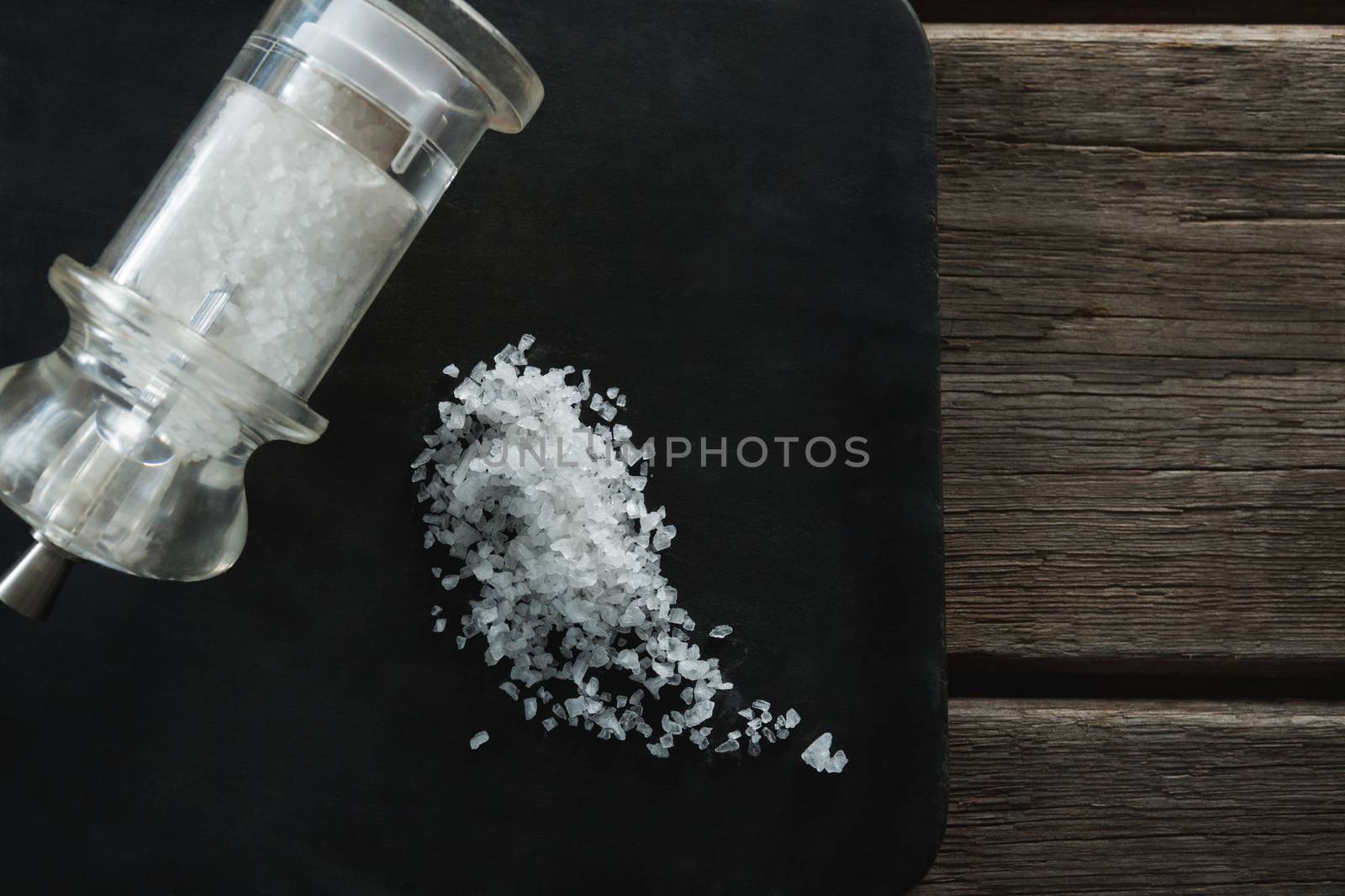 Salt shaker and salt on black slate plate by Wavebreakmedia