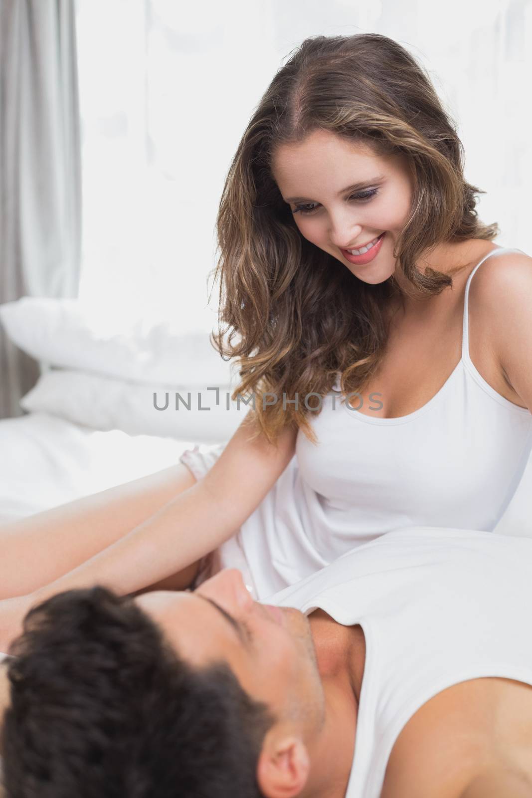 Loving couple in bed at home by Wavebreakmedia