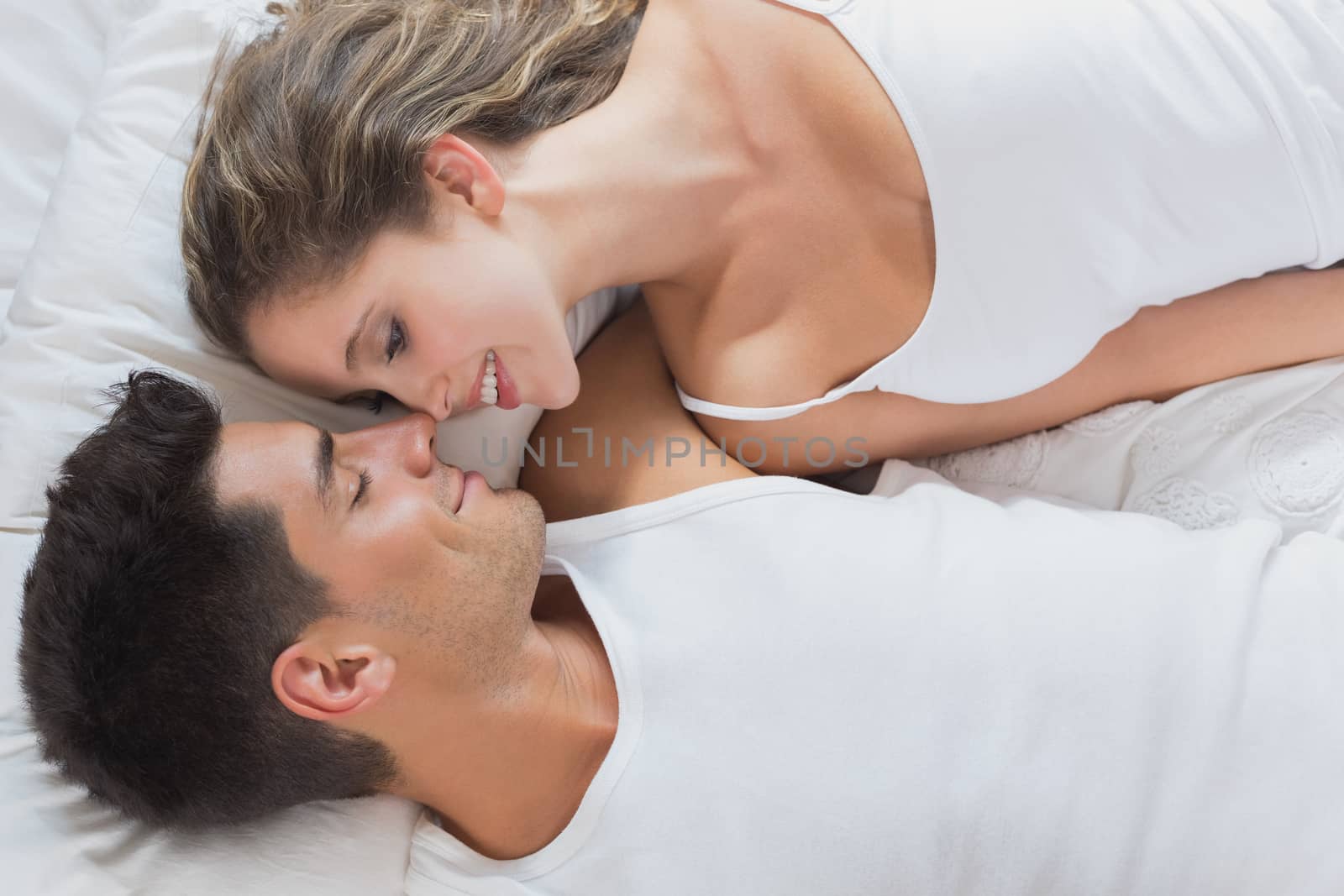 Romantic couple lying in bed at home by Wavebreakmedia