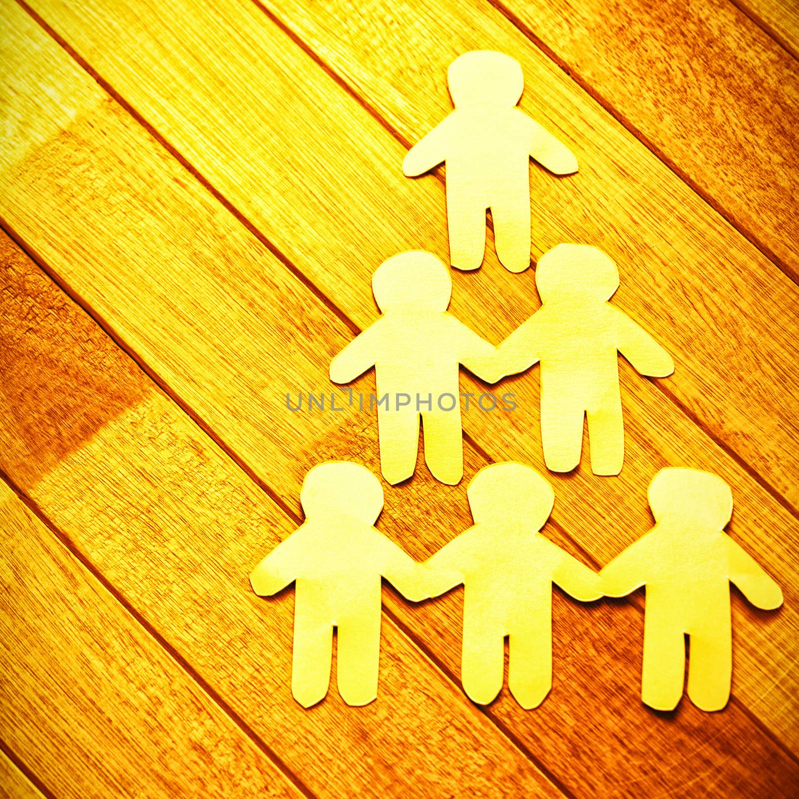 High angle view of paper cut out figures forming human pyramid on wooden table