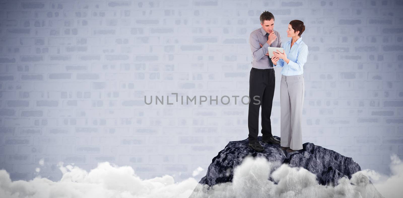 Business people discussing over tablet computer against blue brick background