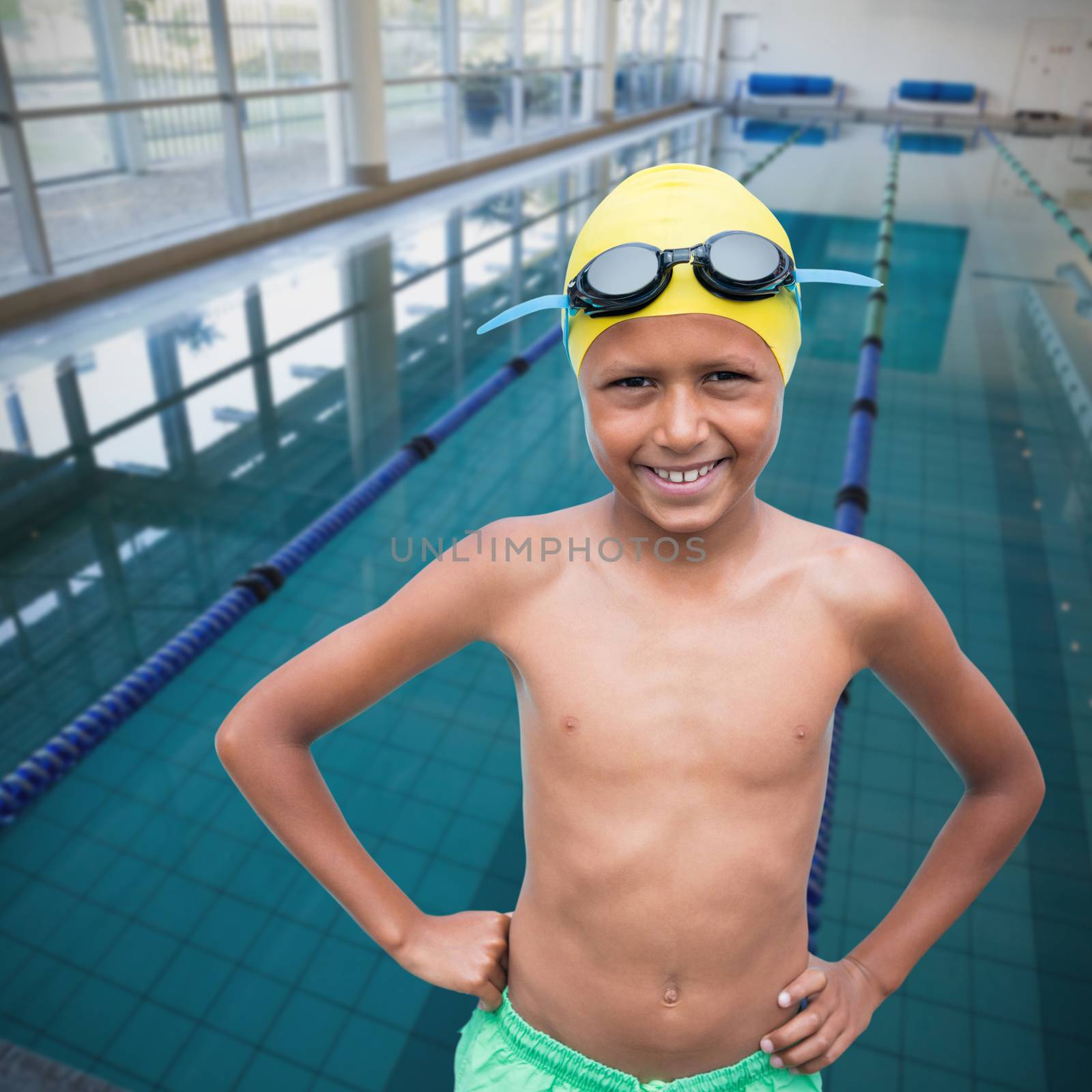 Portrait of cheerful shirtless boy wearing swimming goggles and cap against empty swimming pool with lane markers