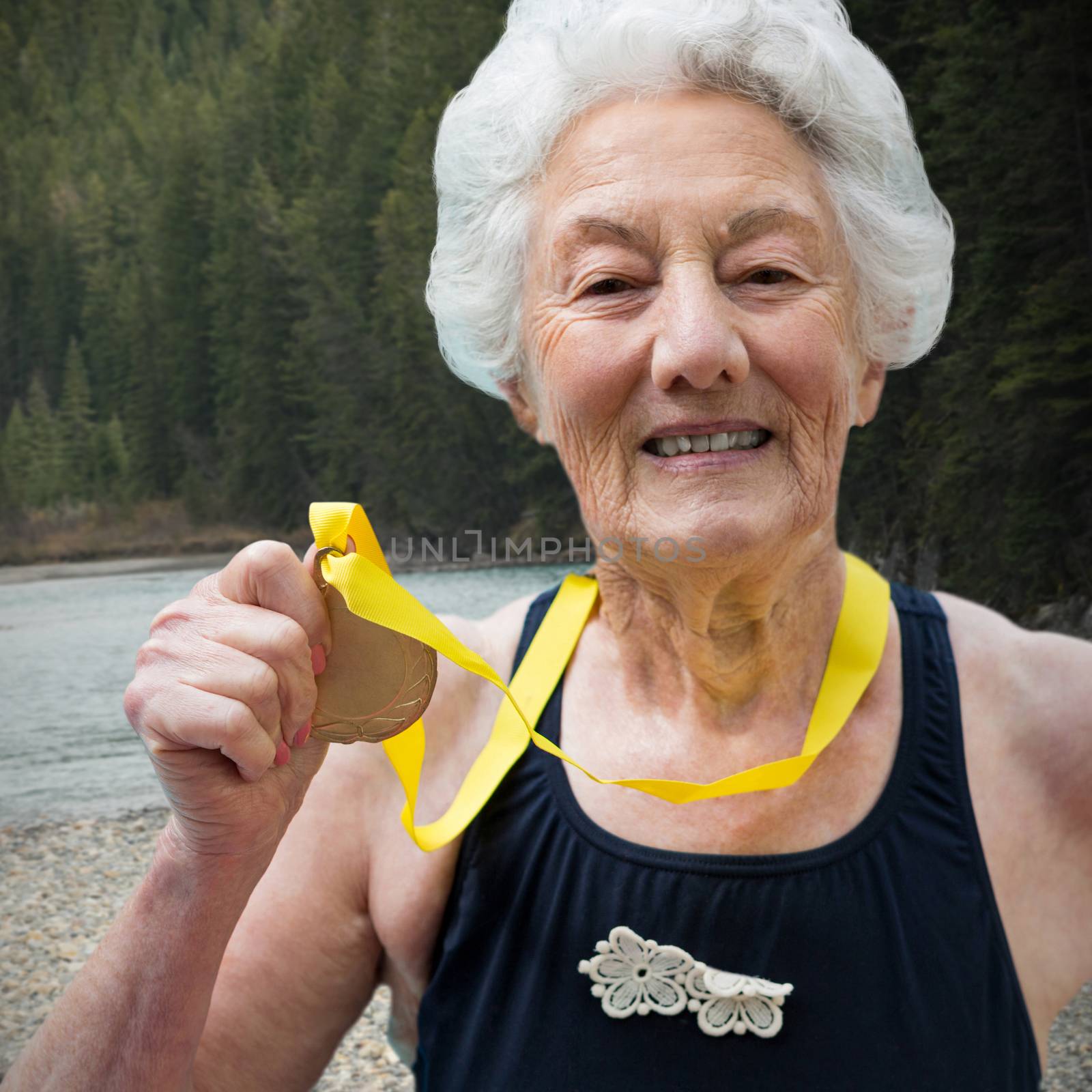 Portrait of female swimmer showing medal against river flowing in forest