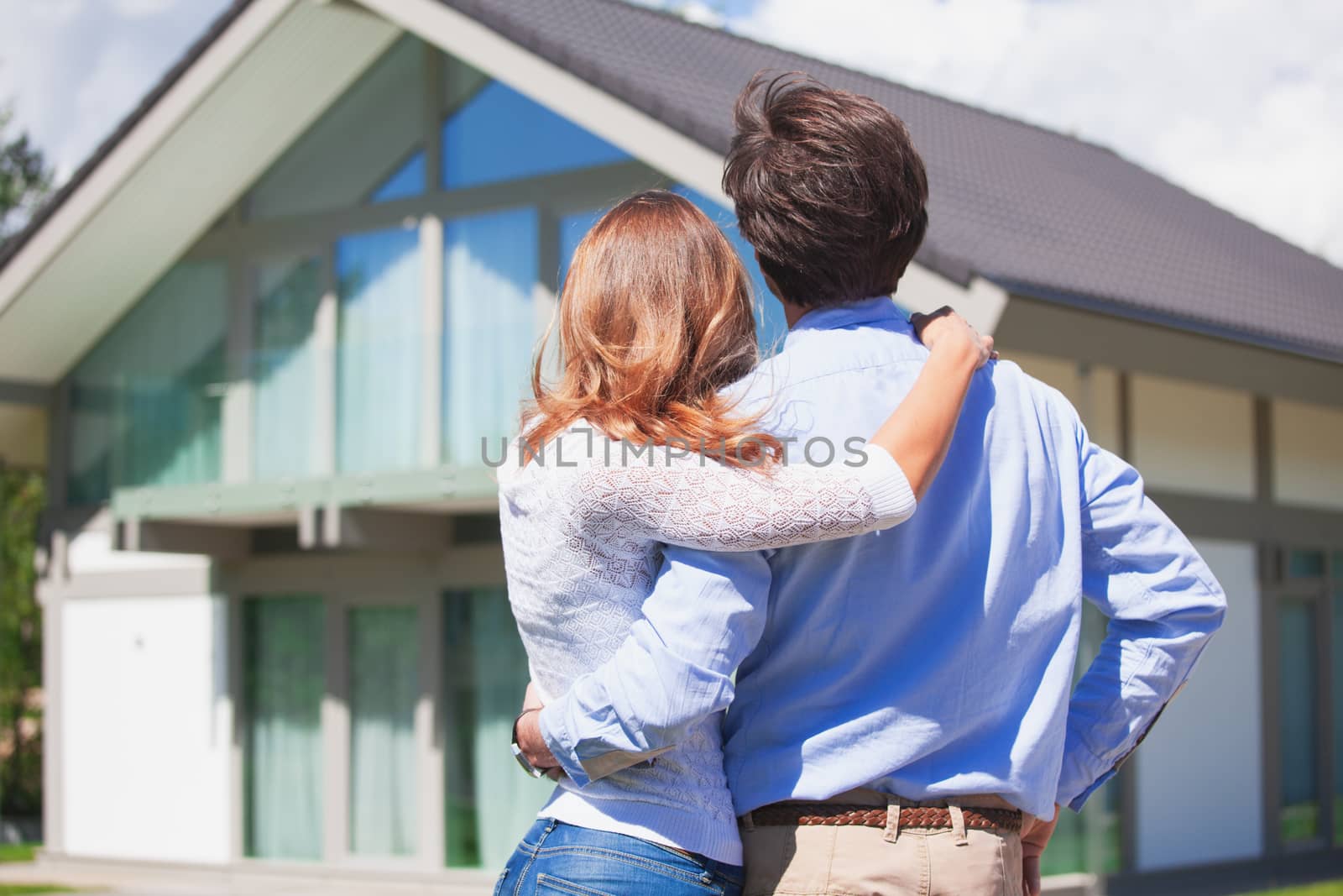 Happy couple stand outdoors hug and look at their new house