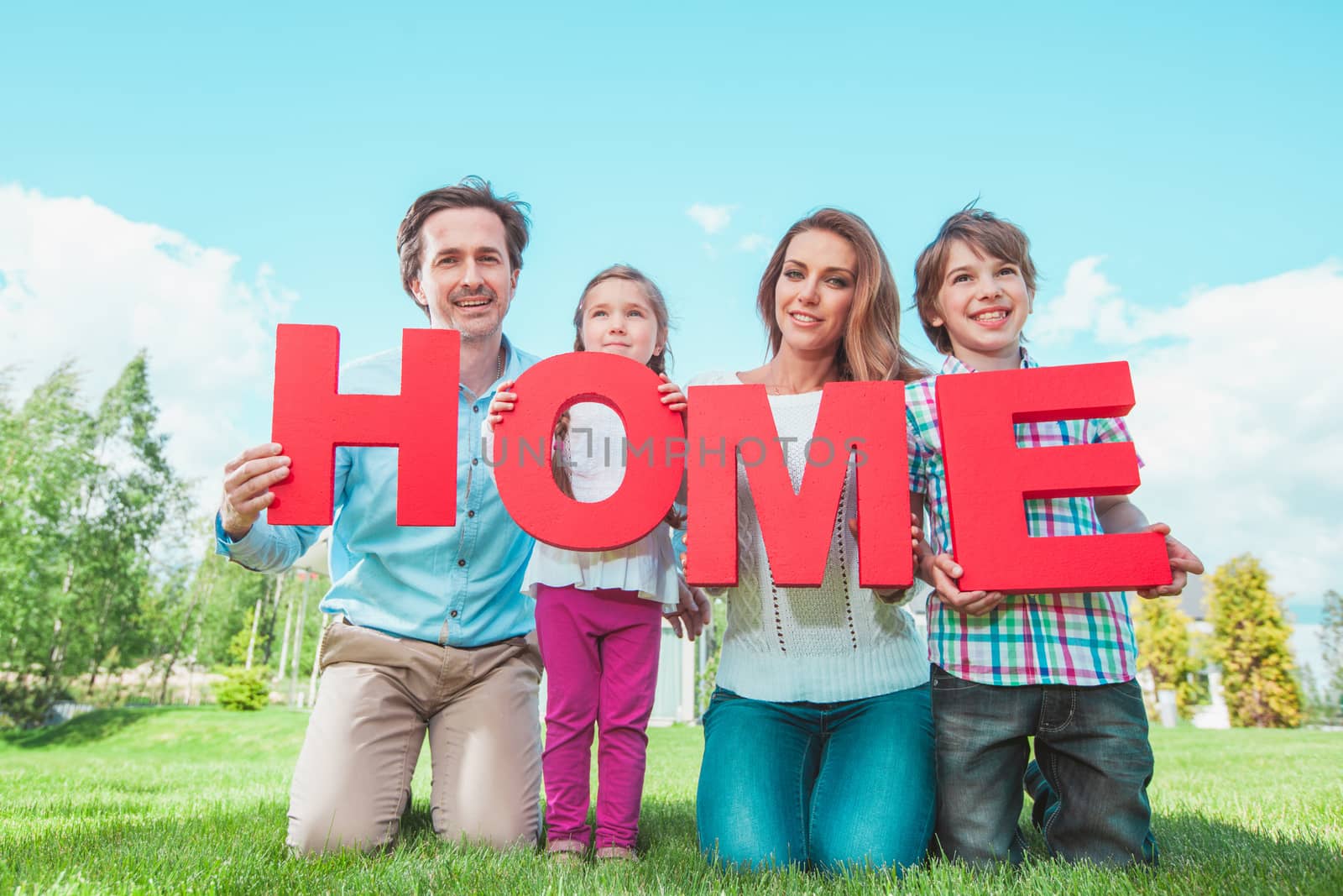 Happy family holding HOME letters in front of their house