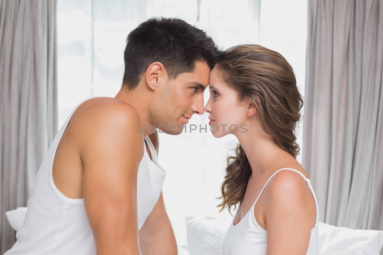 Side view of romantic young couple sitting in bed at home