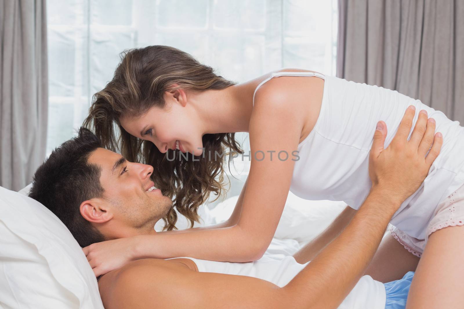 Side view of romantic young couple in bed at home