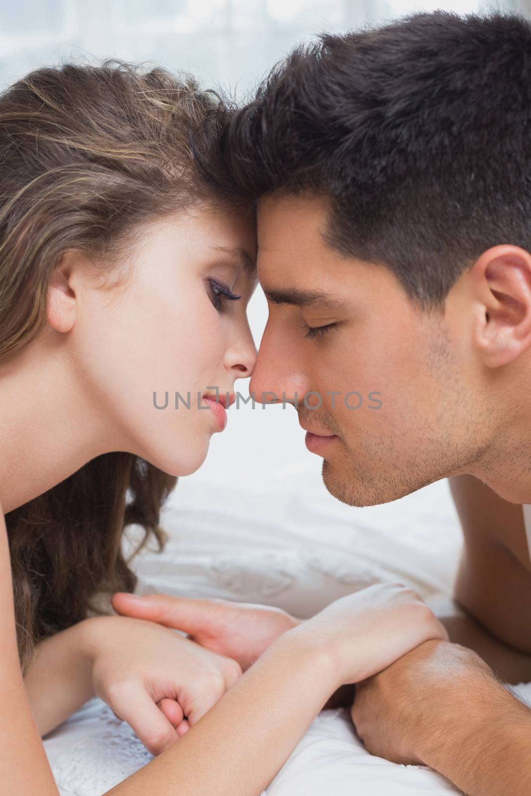 Close up side view of romantic young couple in bed at home