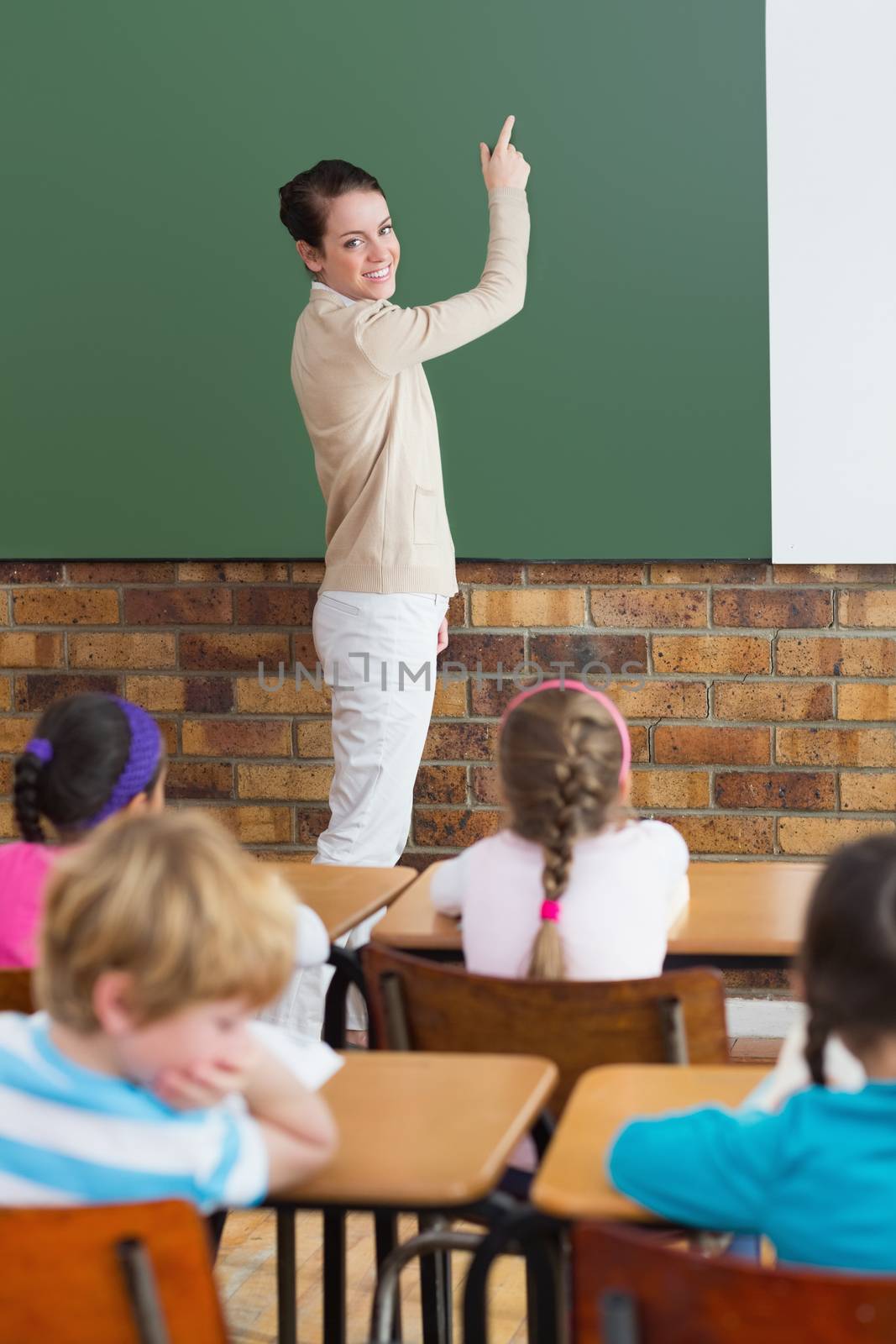 Cute pupils listening to their teacher in classroom at the elementary school