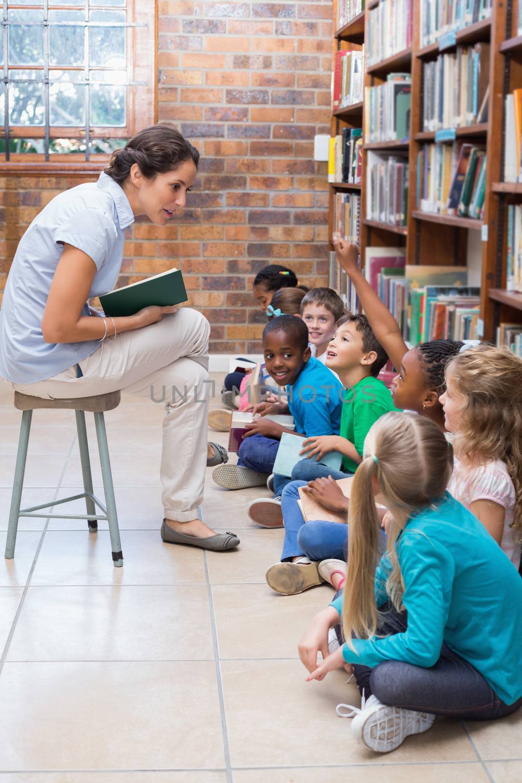 Cute pupils sitting on floor in library by Wavebreakmedia