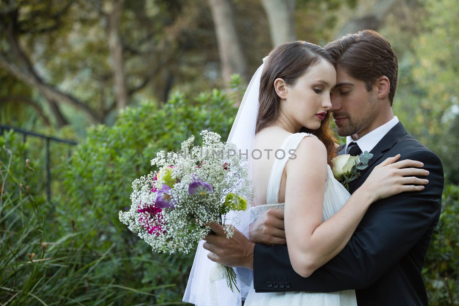Romantic couple with eyes closed embracing while standing in park