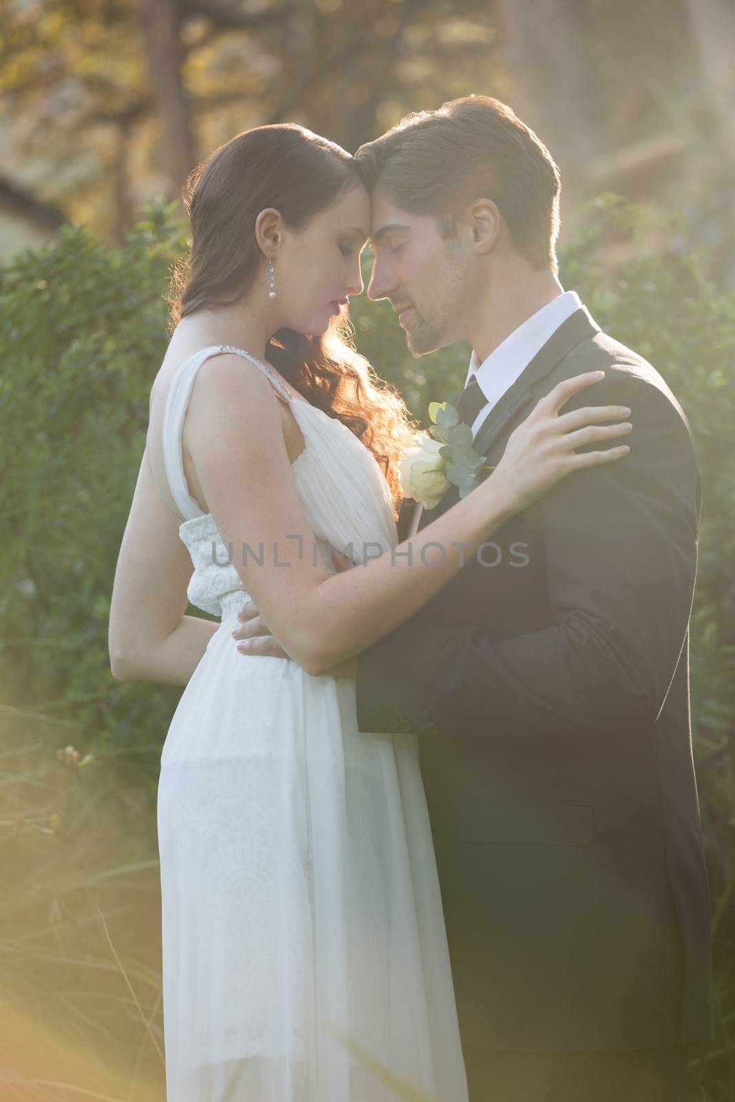 Romantic newlywed couple with eyes closed standing at park by Wavebreakmedia