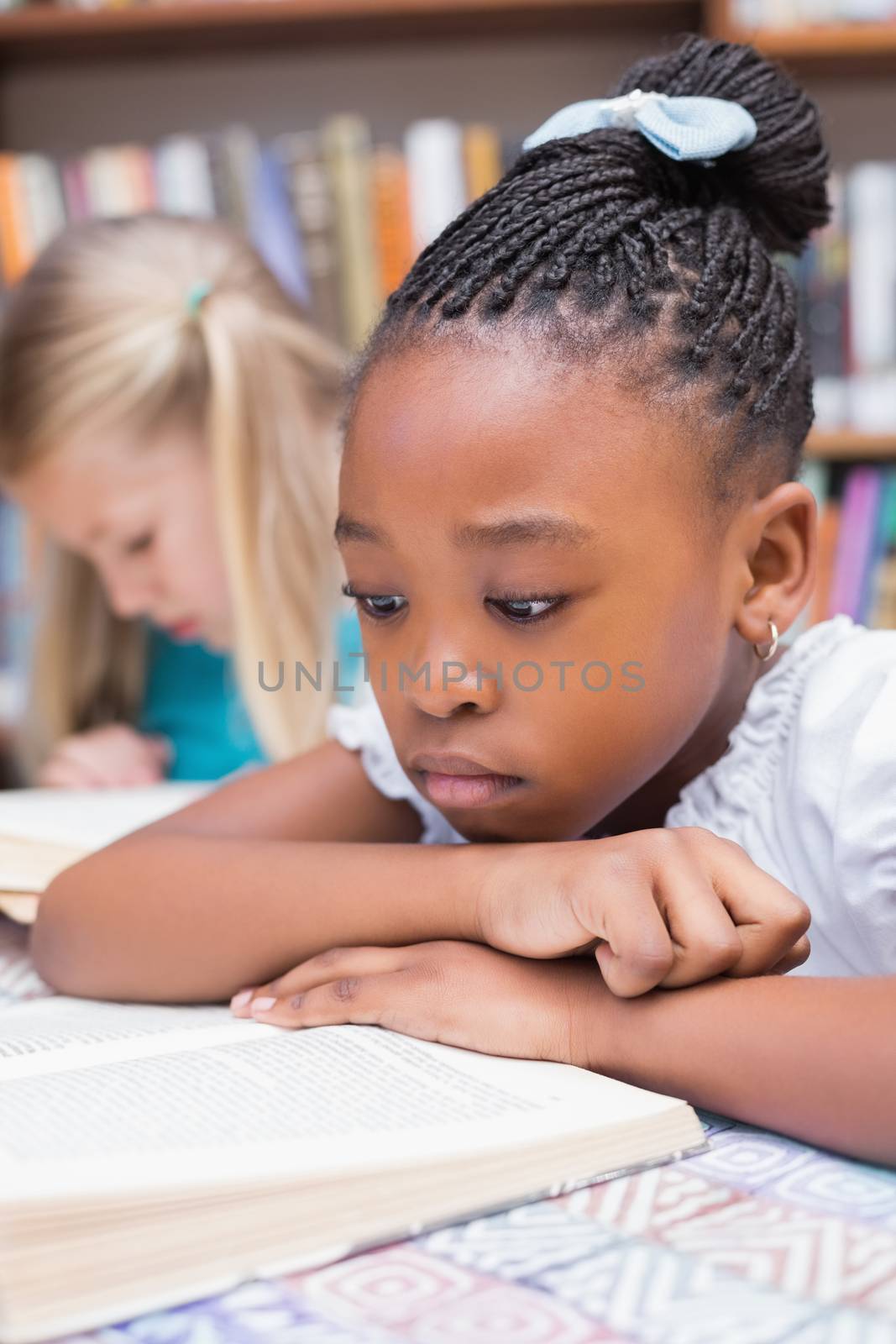 Cute pupils reading books in library at the elementary school
