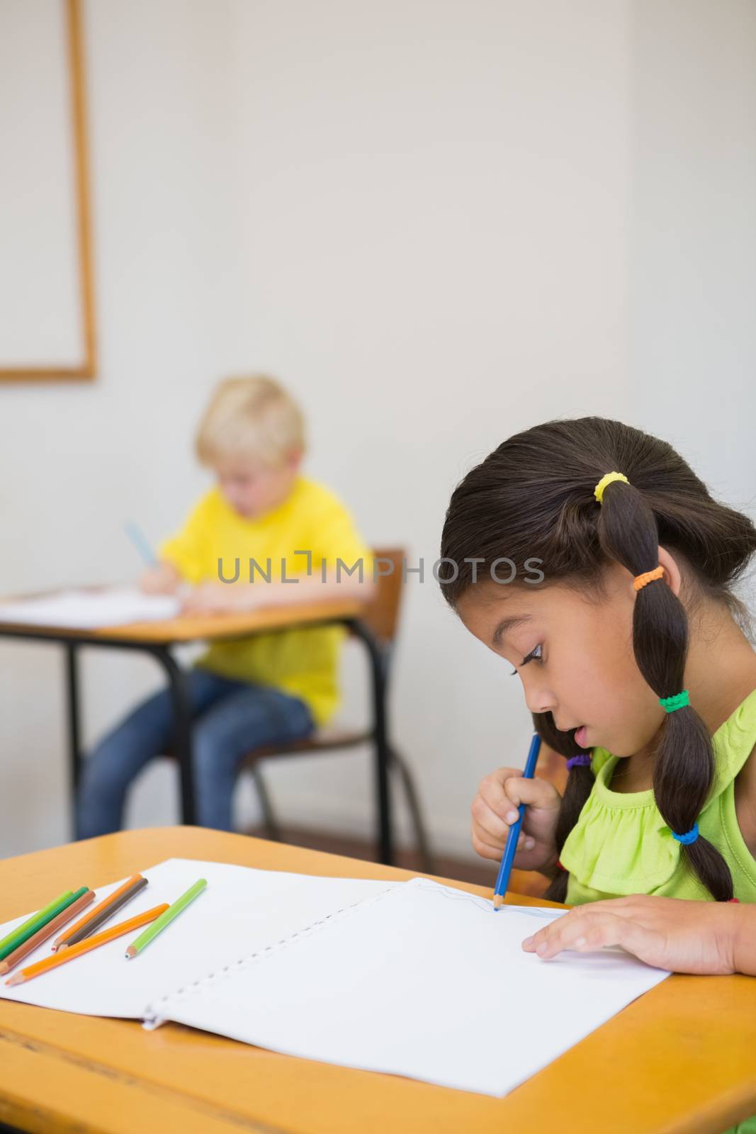 Cute pupils colouring at desks in classroom at the elementary school