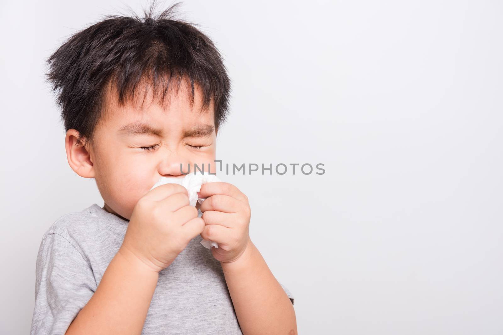 Closeup Asian face, Little children boy cleaning nose with tissue on white background with copy space, health medical care