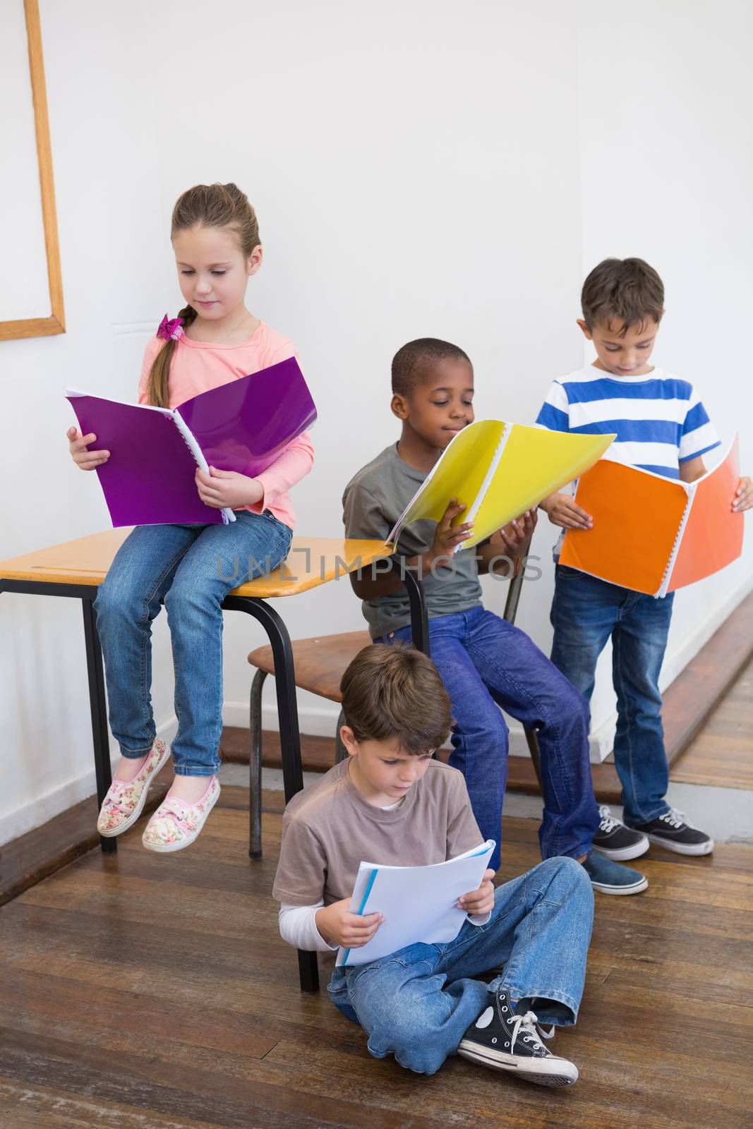 Classmates reading from notepads in classroom at the elementary school