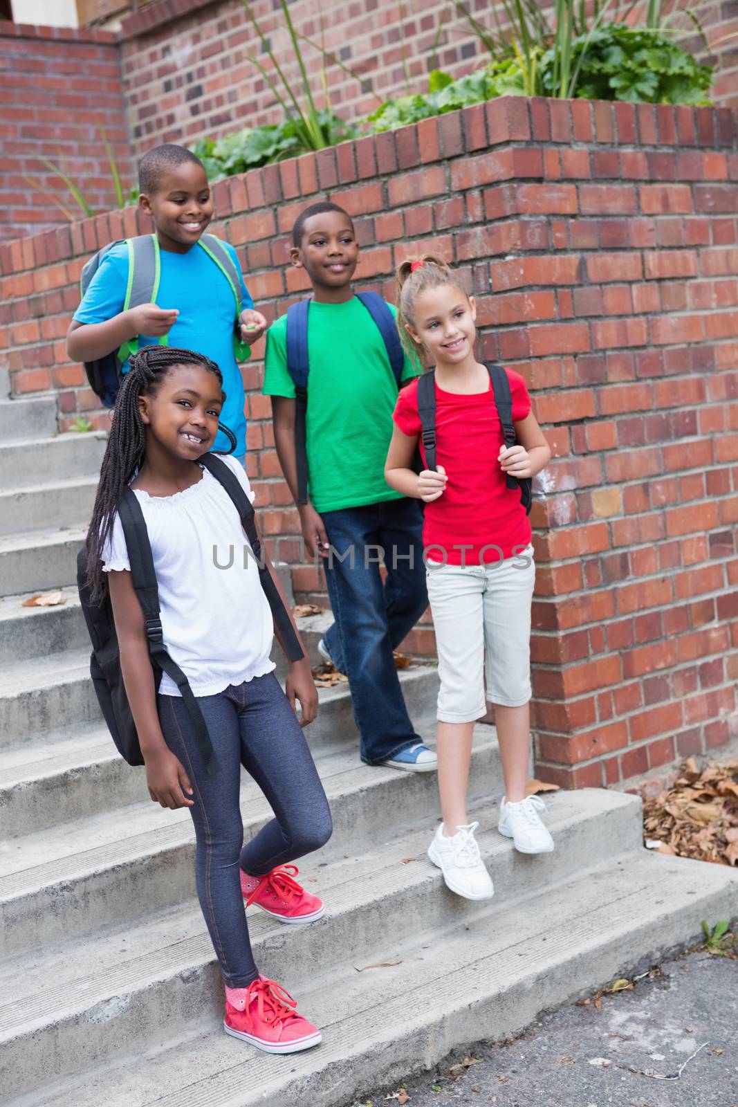 Cute pupils smiling on the stairs outside at the elementary school