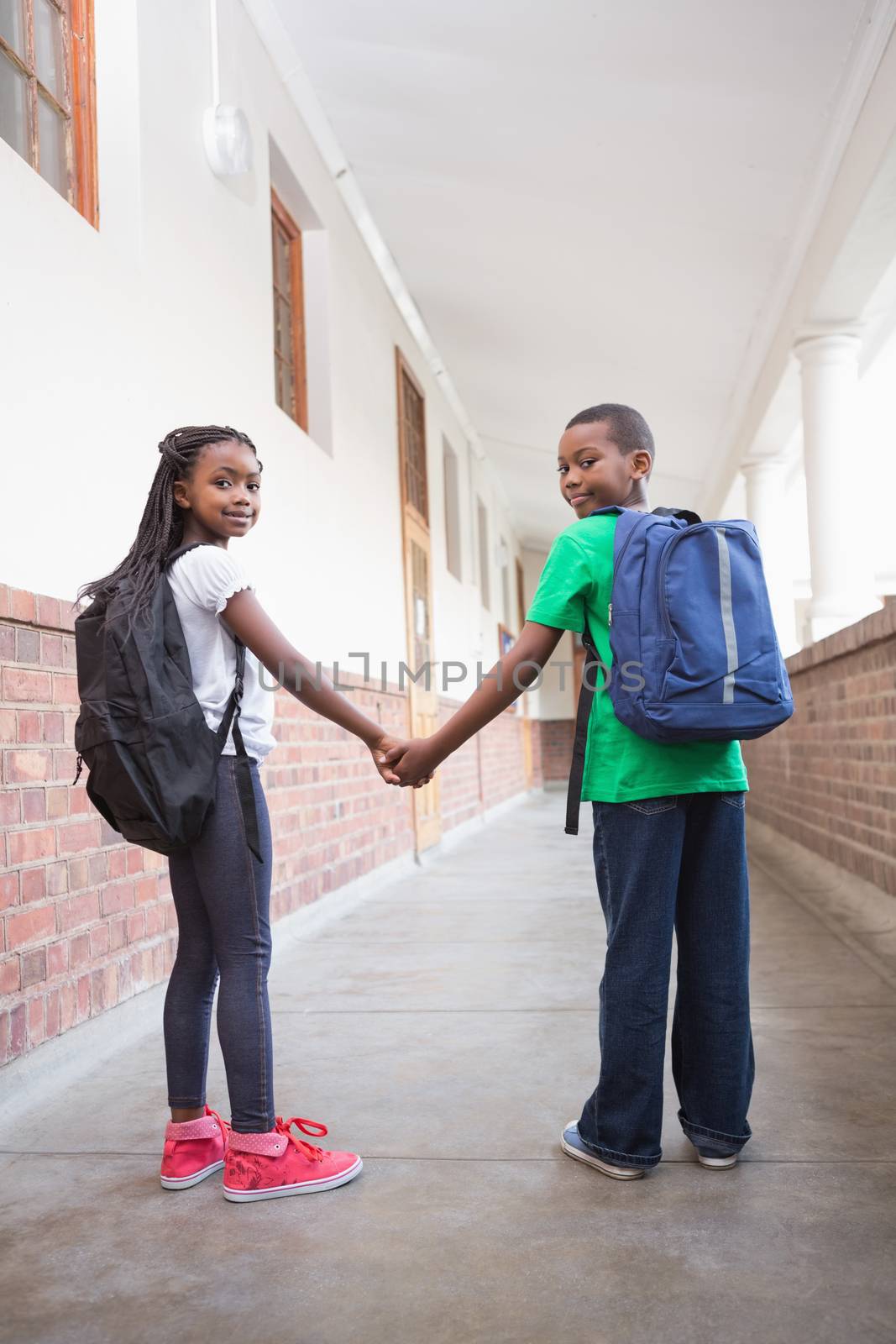 Cute pupils holding hands in corridor by Wavebreakmedia