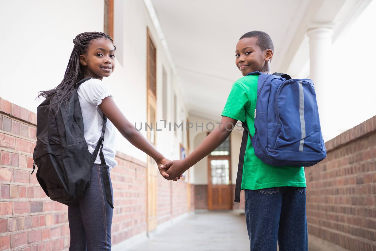 Cute pupils holding hands in corridor at the elementary school