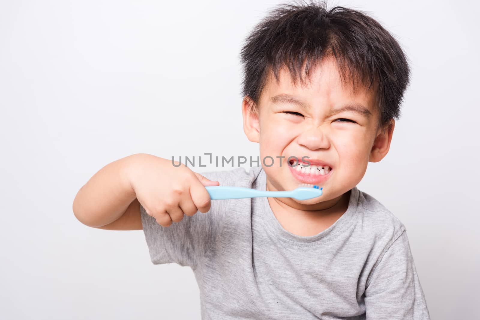 Closeup Asian face, Little children boy hand holds toothbrush he by Sorapop