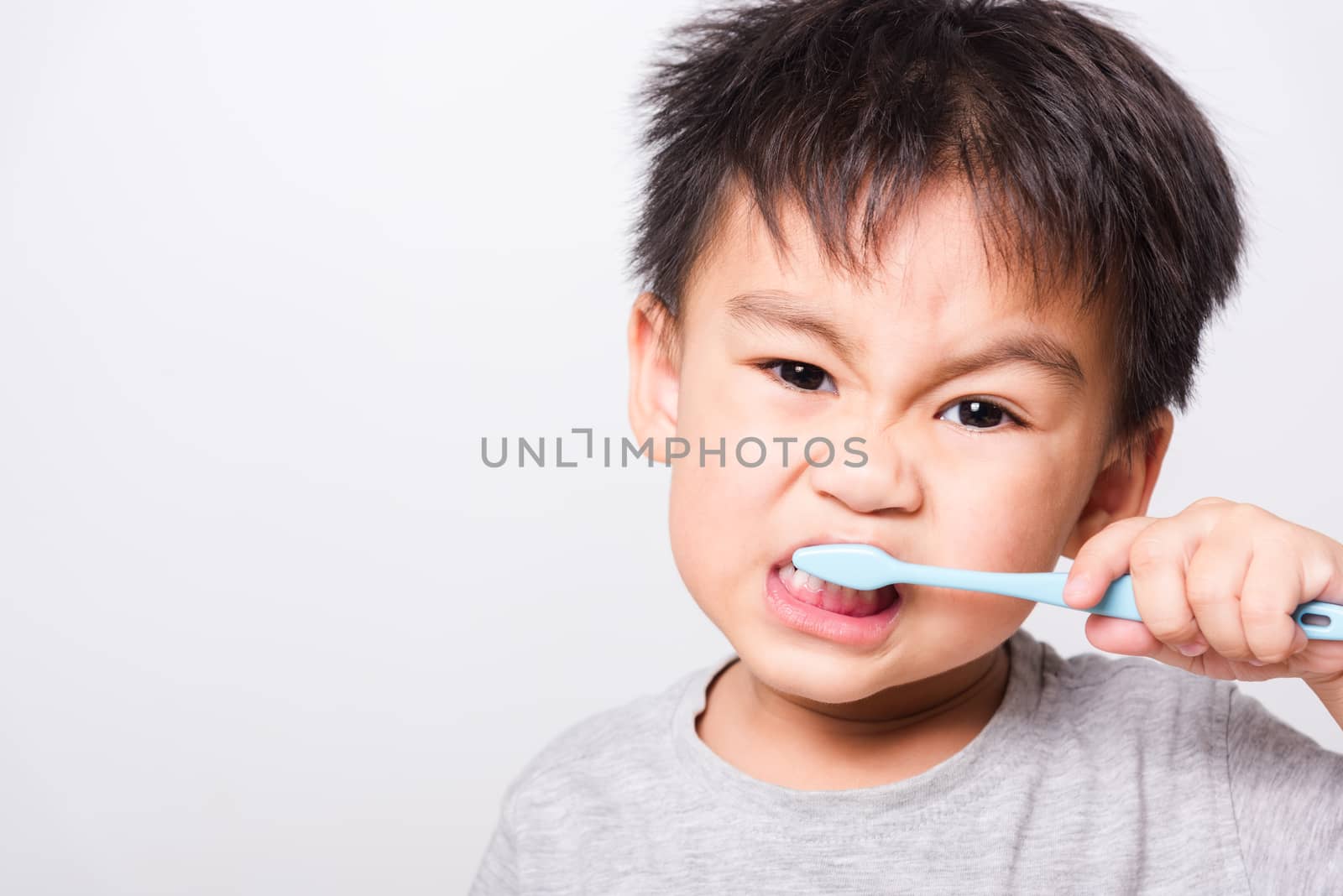 Closeup Asian face, Little children boy hand holds toothbrush he by Sorapop