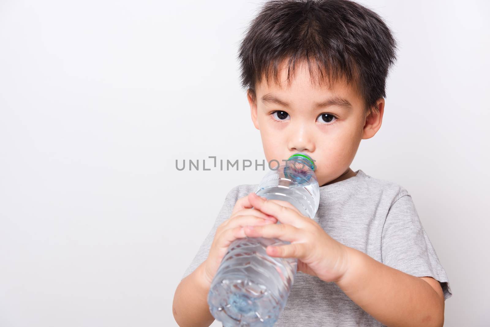 Closeup Asian face, Little children boy drinking water from Plastic bottle on white background with copy space, health medical care