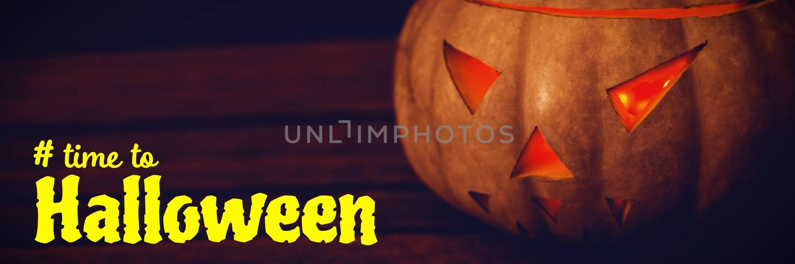 Digital image of time to Halloween text against close up of illuminated jack o lantern on table during halloween