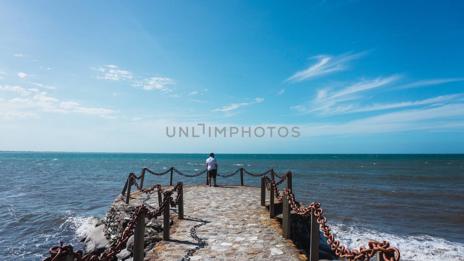 Along man on the pier enjoying the sun and the beautiful of the sea