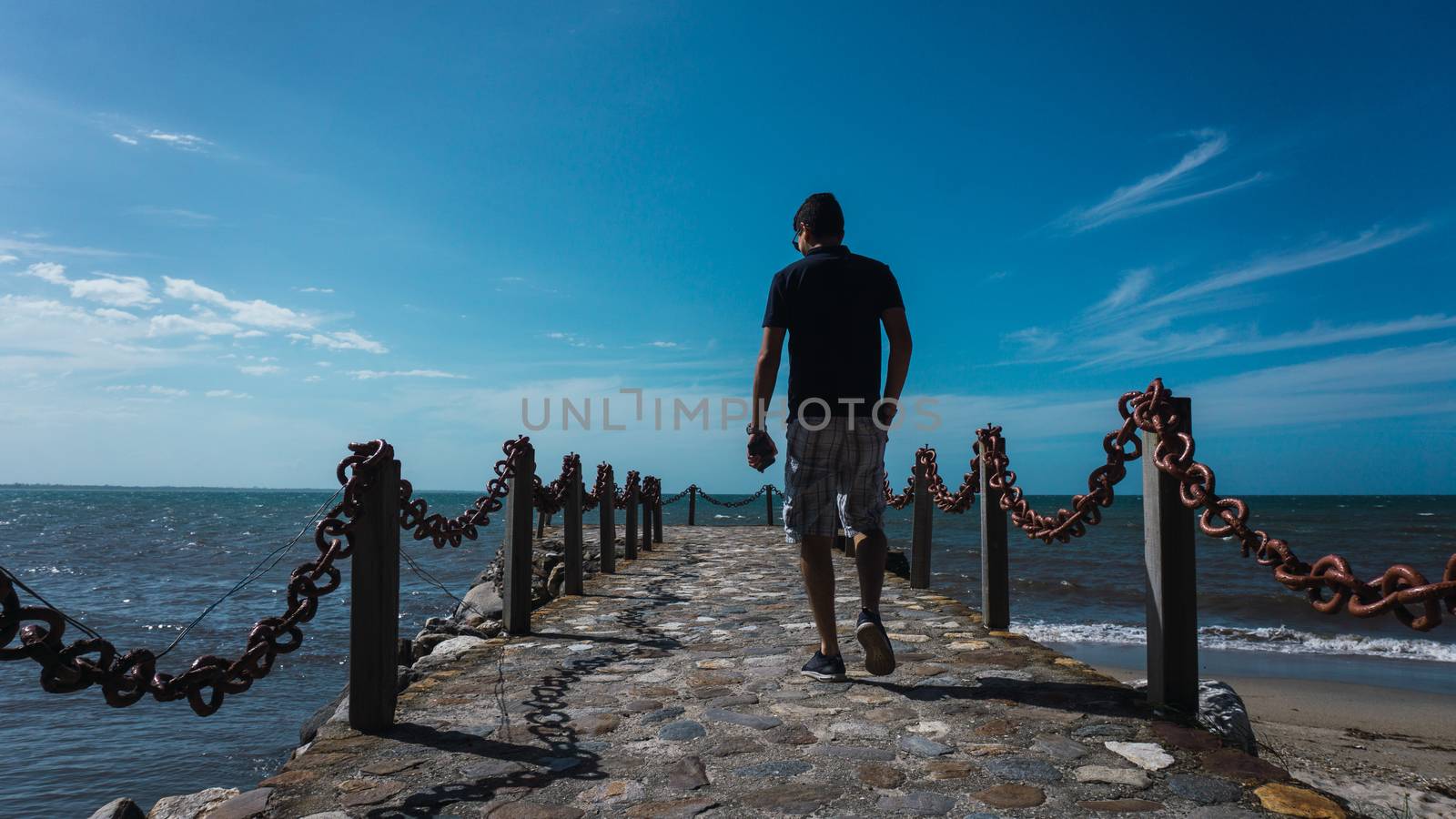 Along man on the pier enjoying the sun and the beautiful of the sea