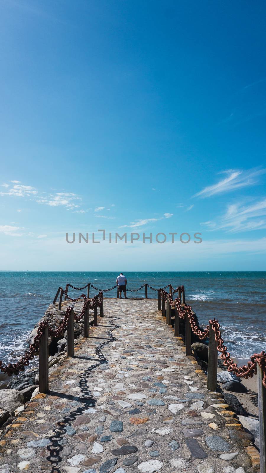 Along man on the pier enjoying the sun and the beautiful of the sea