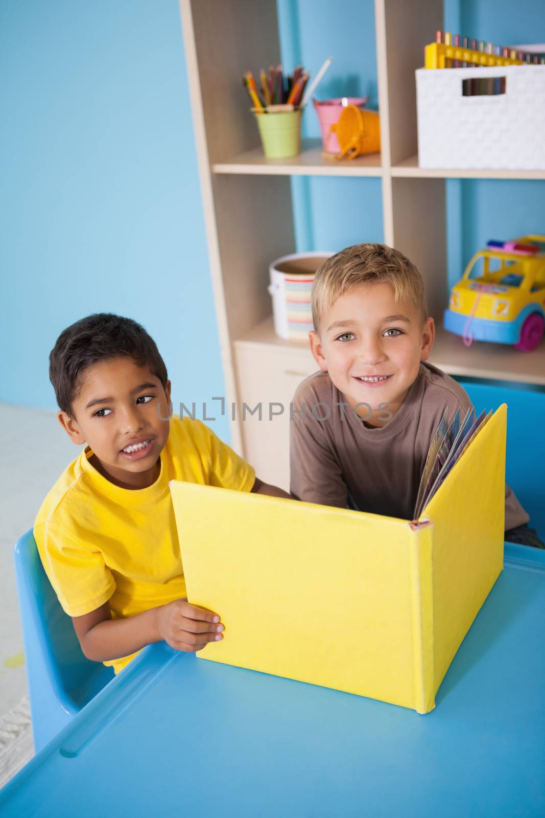 Cute little boys reading at desk in classroom by Wavebreakmedia