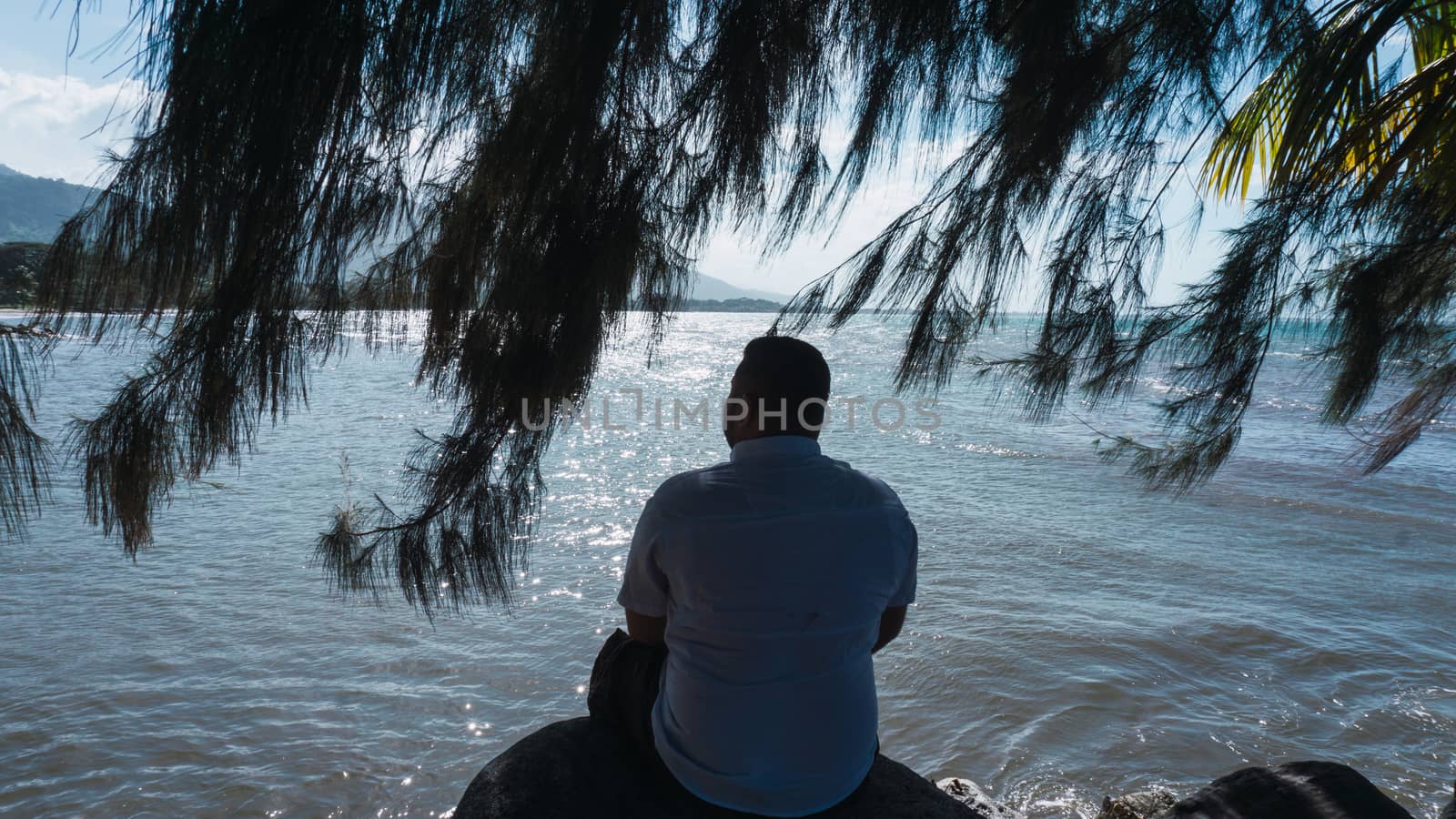Along man sitting on a rock relaxing and reflexion with a beautiful blue sky and sea
