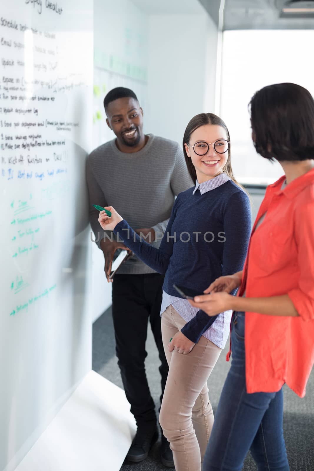 Male and female executives discussing on whiteboard in office