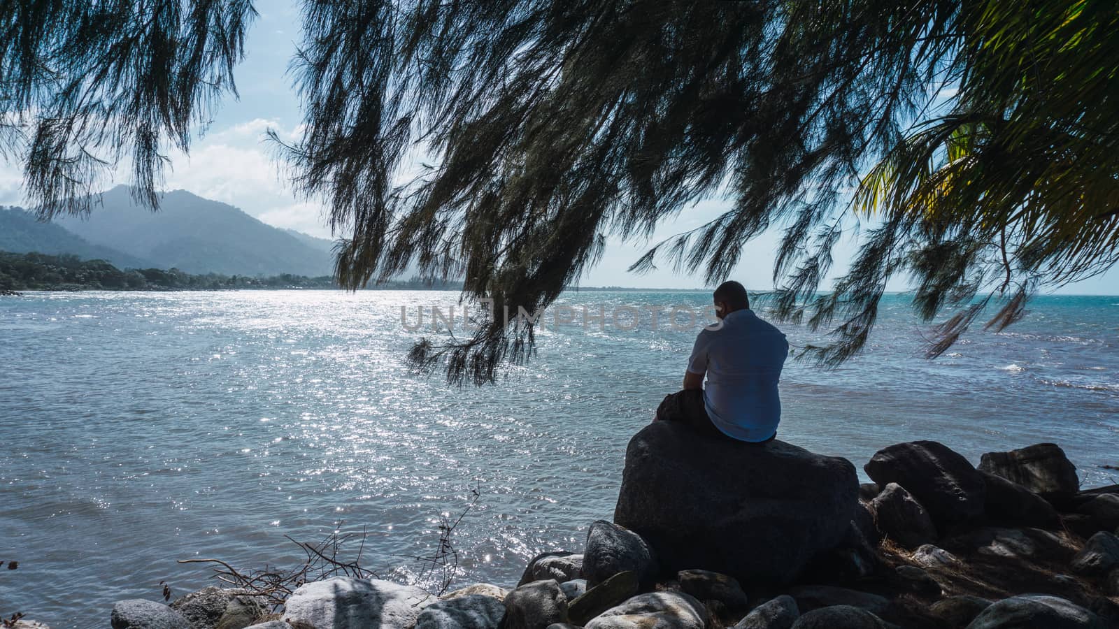 Along man sitting on a rock relaxing and reflexion with a beautiful blue sky and sea by henrry08