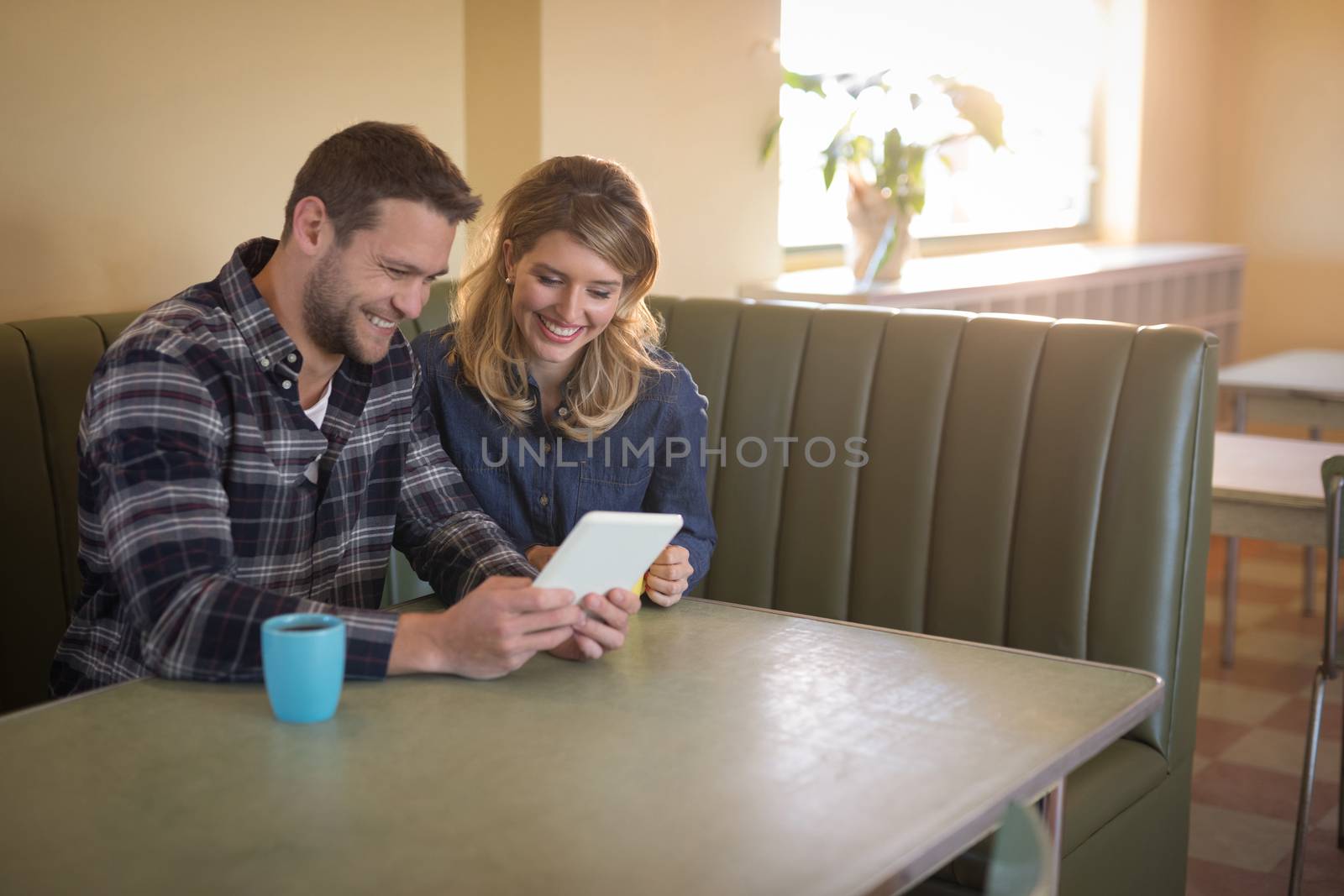 Romantic couple using digital tablet in restaurant