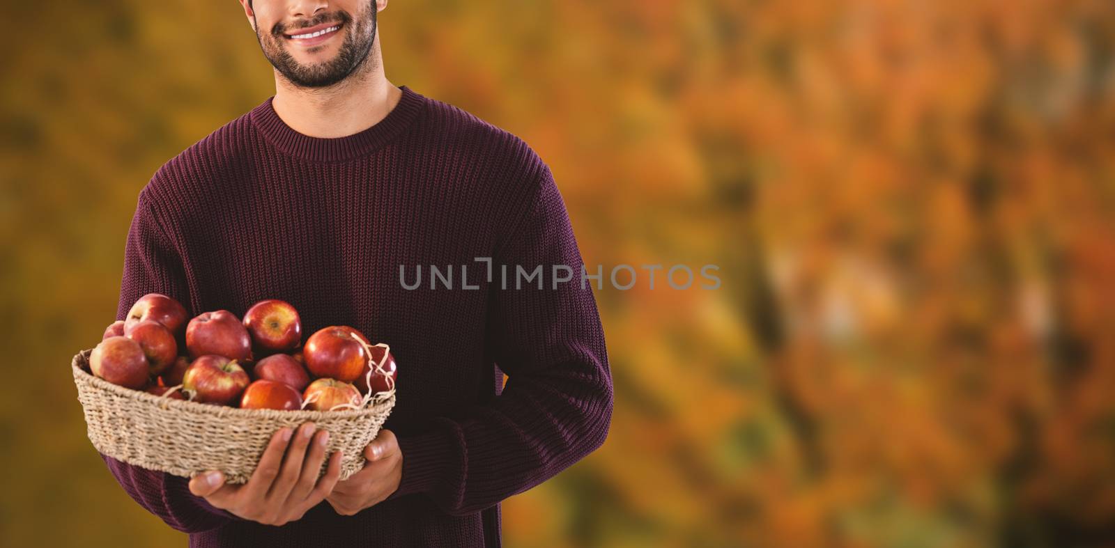 Portrait of man holding basket with apples against tree growing outdoors