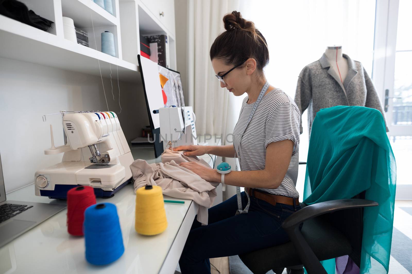 Fashion designer using sewing machine at home