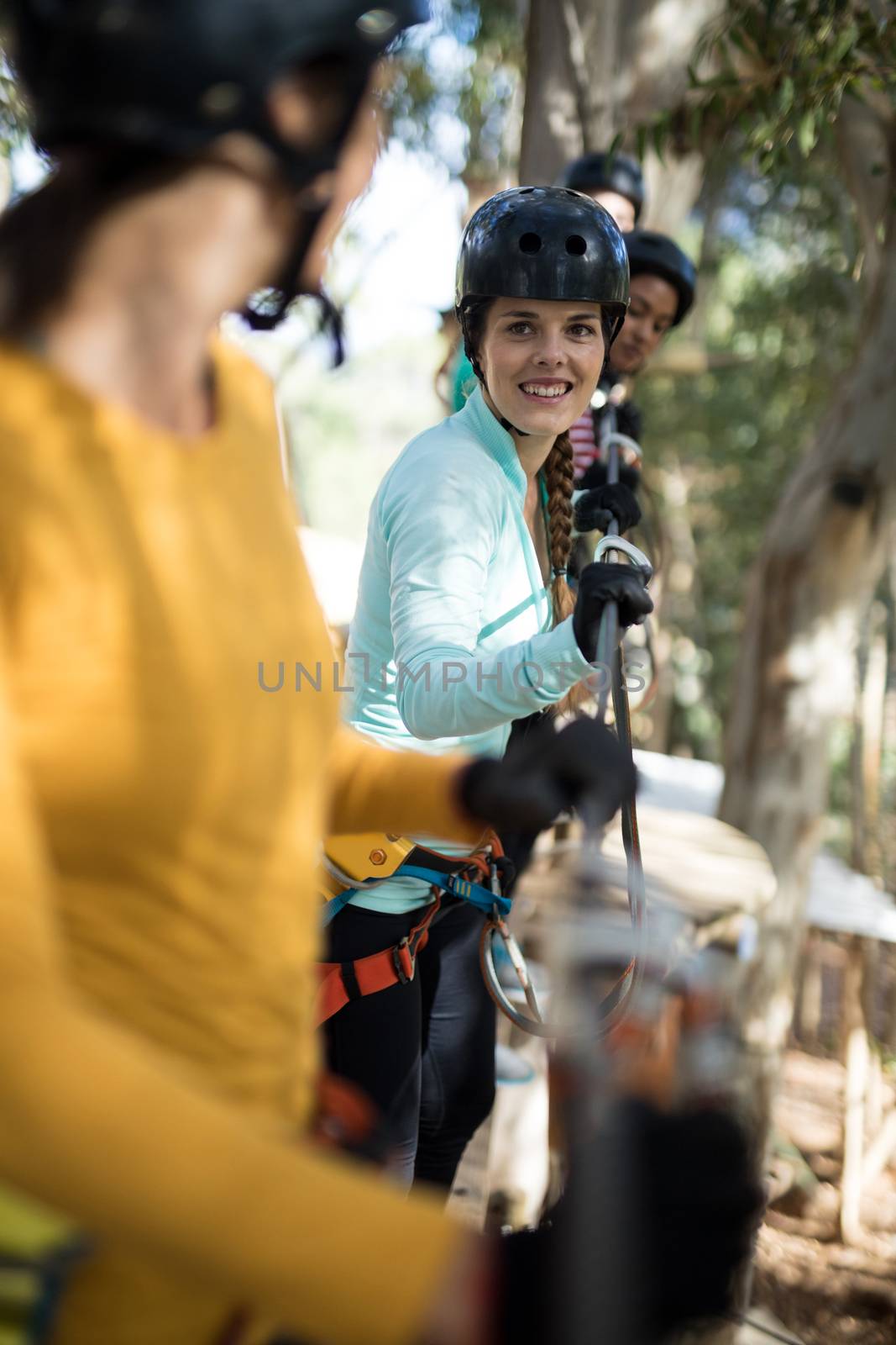 Friends enjoying zip line adventure in park on a sunny day