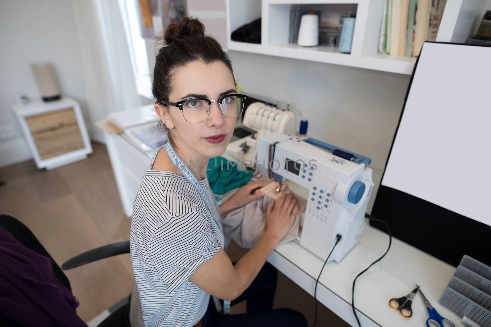 Fashion designer using sewing machine at home