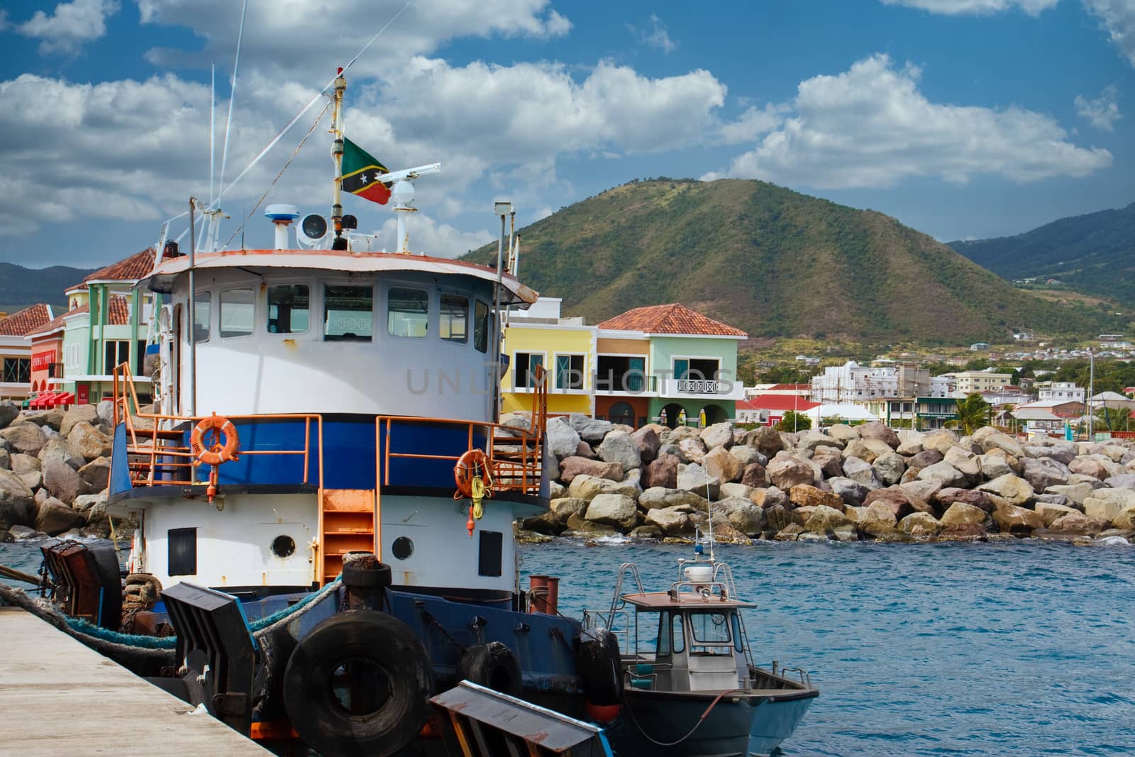 An old blue and white tugboat tied up to a dock on the island of St. Kitts in the Caribbean