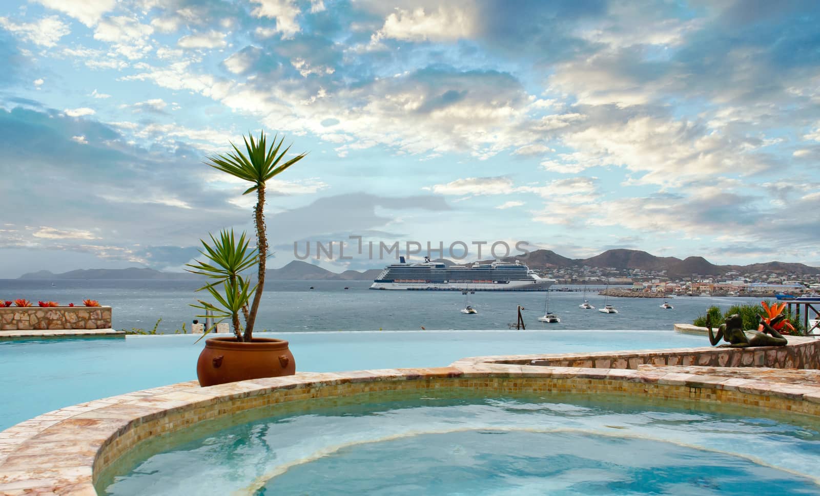 A luxury cruise ship anchored across the bay from a tropical swimming pool