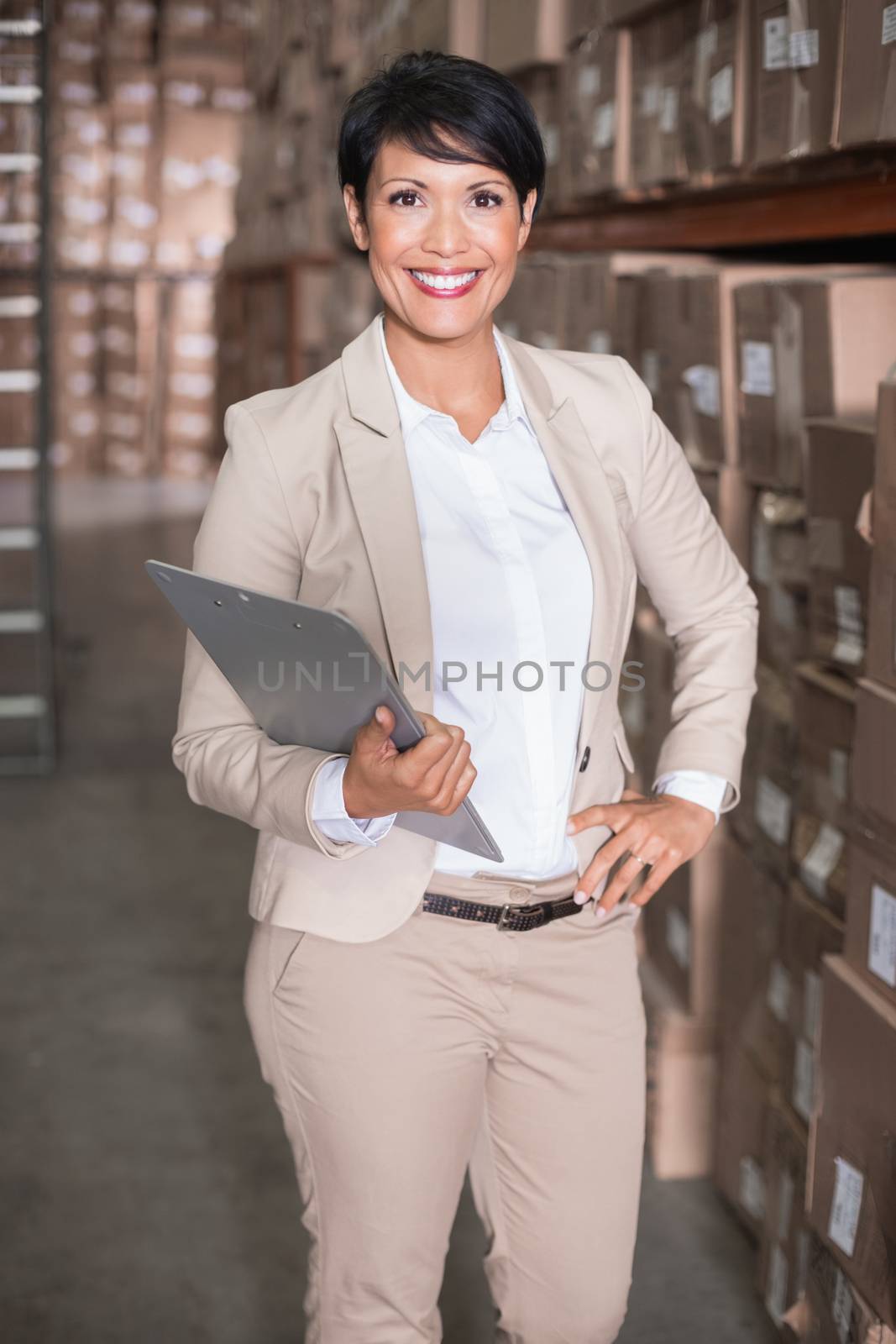 Pretty warehouse manager smiling at camera in a large warehouse