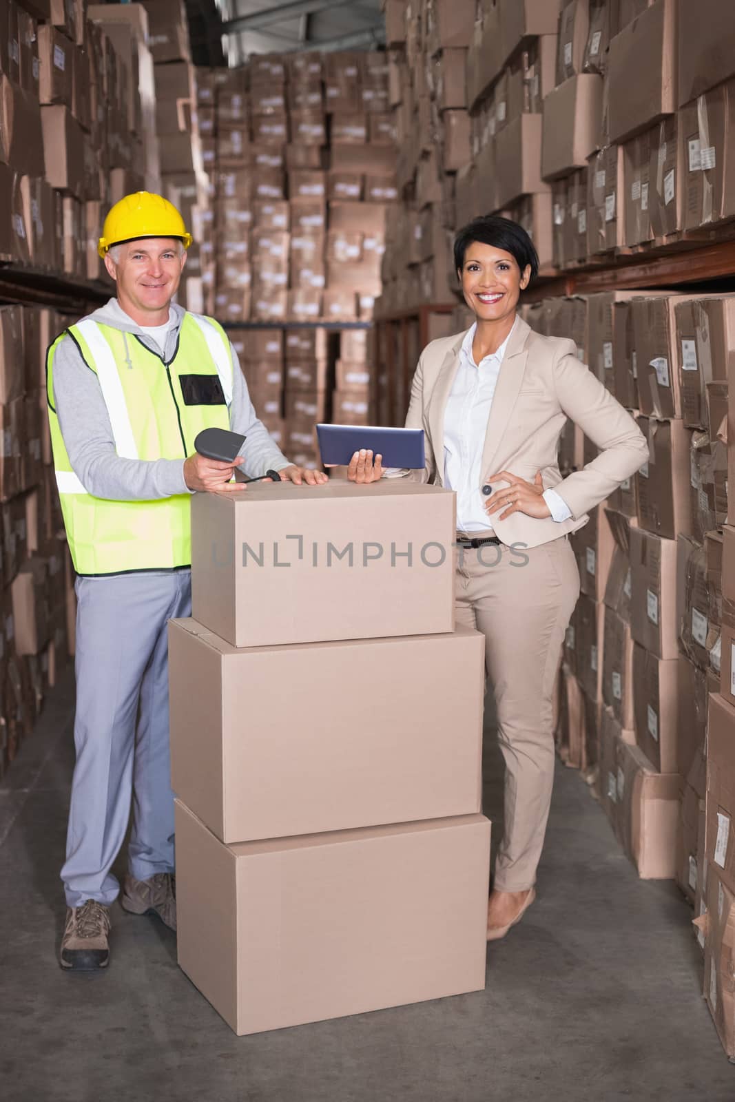 Warehouse worker scanning box with manager holding tablet pc by Wavebreakmedia