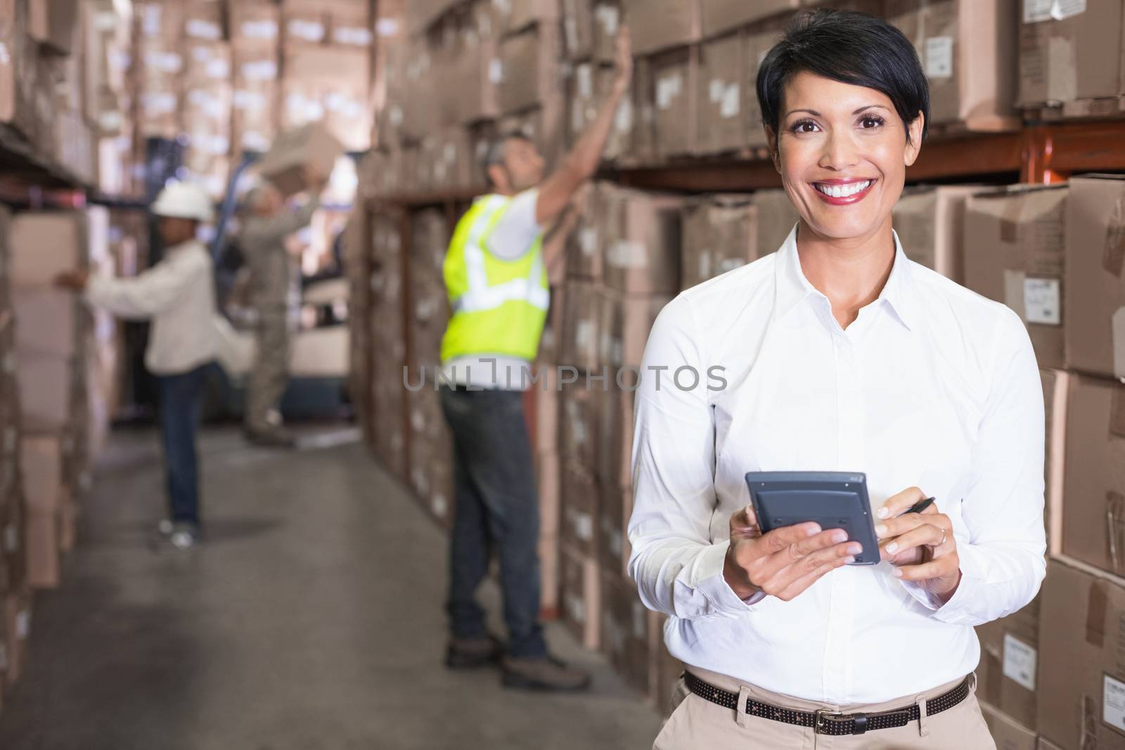 Pretty warehouse manager using calculator in a large warehouse