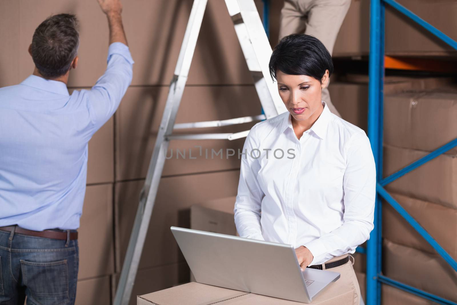 Pretty warehouse manager using laptop in a large warehouse