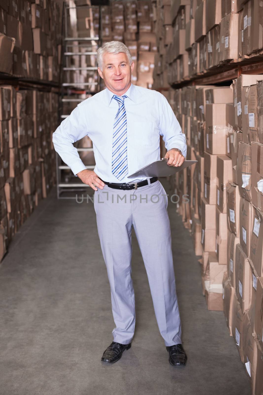 Warehouse manager smiling at camera in a large warehouse