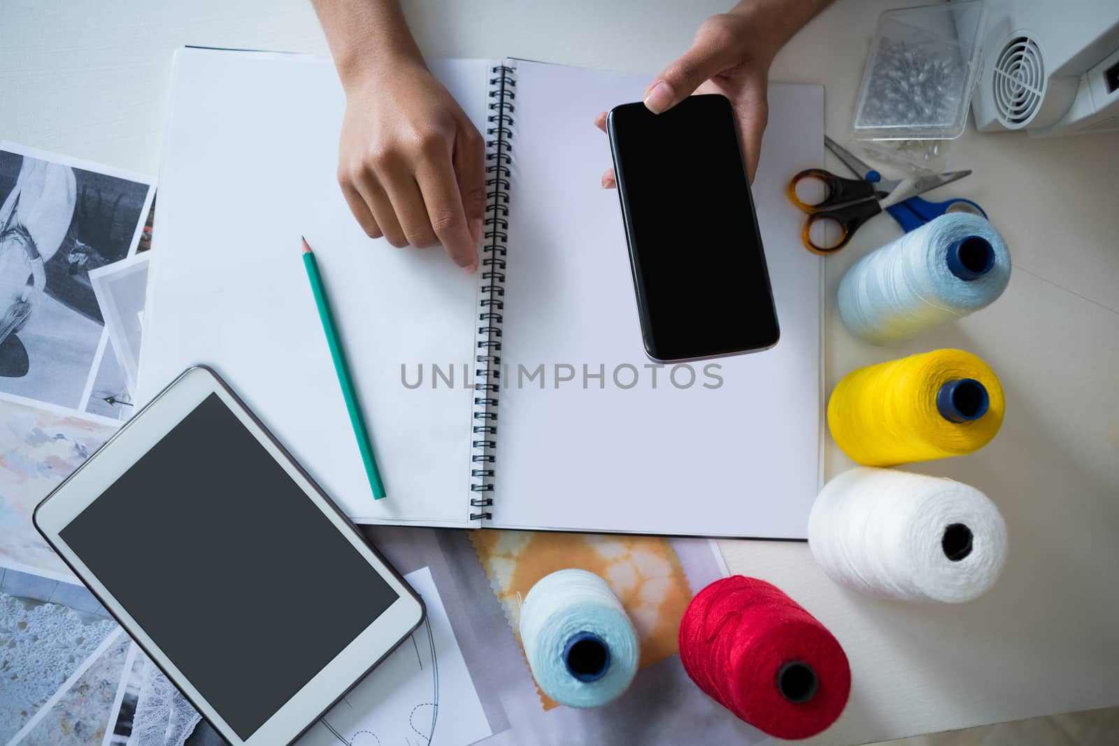 Overhead of fashion designer using mobile phone at desk