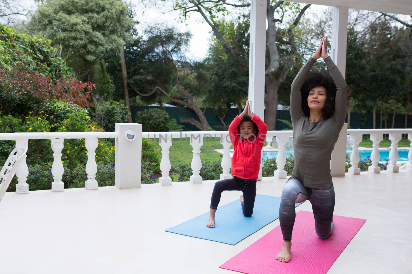 Mother and daughter performing yoga in the porch by Wavebreakmedia