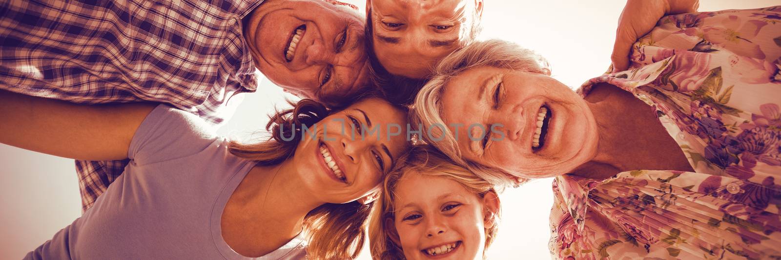 Portrait of cheerful family forming huddle against sky