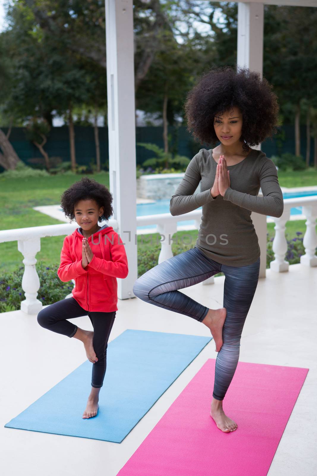 Mother and daughter performing yoga in the porch by Wavebreakmedia